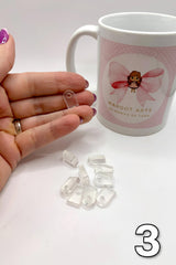 Hand holding clear plastic clips with a branded mug in the background