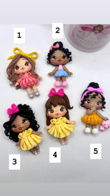 Five small dolls with different hairstyles and outfits on a white background.